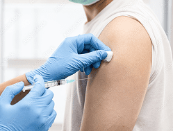 A healthcare worker wearing blue gloves prepares to administer a vaccine injection into a person's upper arm.